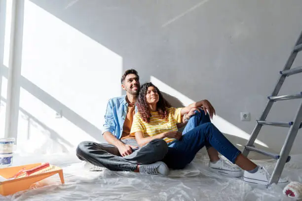 Young couple smiling in their new home needing renovations