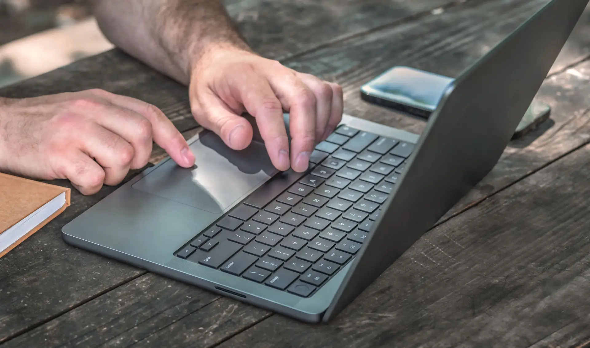 Hands of a self-employed borrower working on a laptop reviewing income paperwork